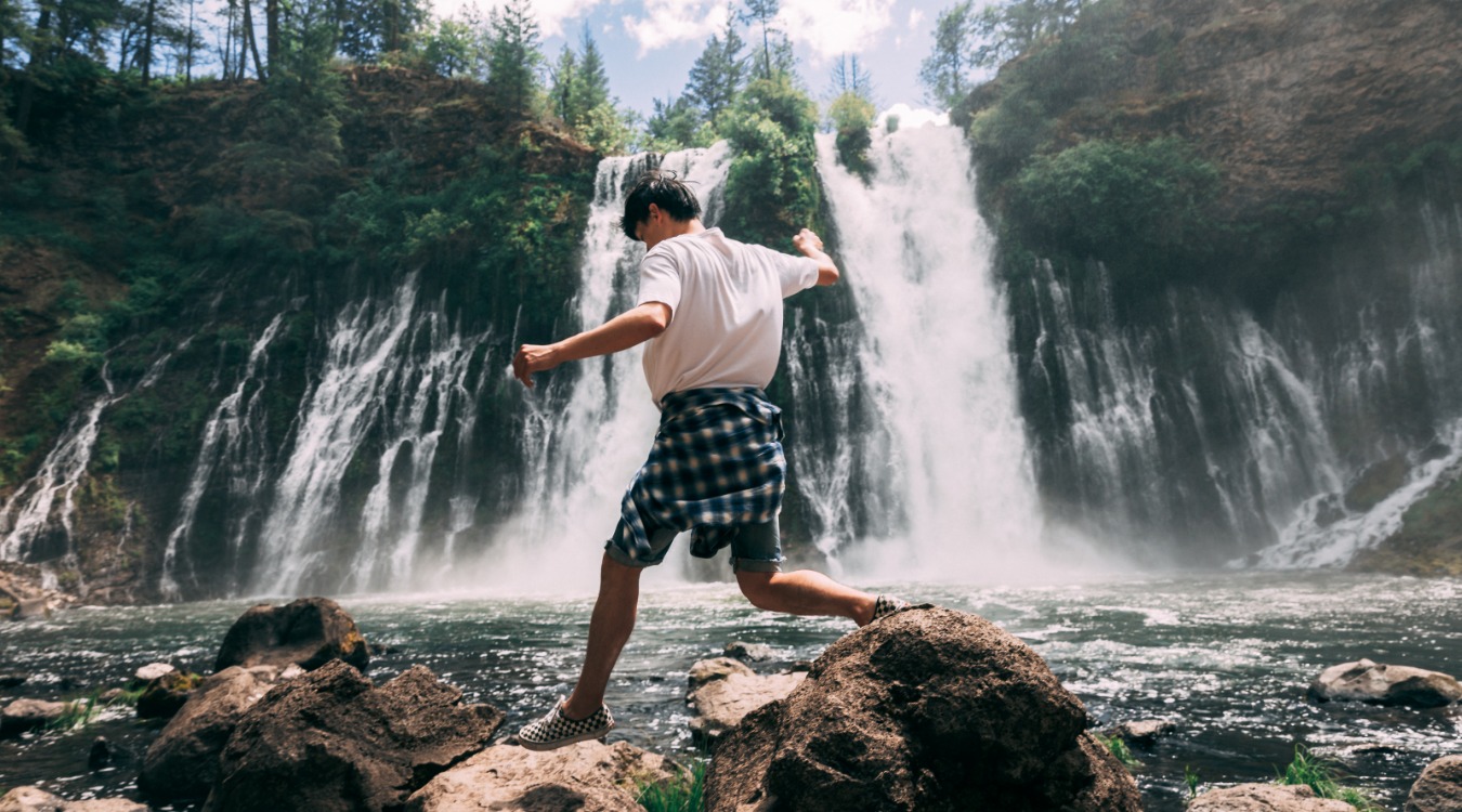 Man jumping across rocks at McArthur-Burney Falls Memorial State Park.